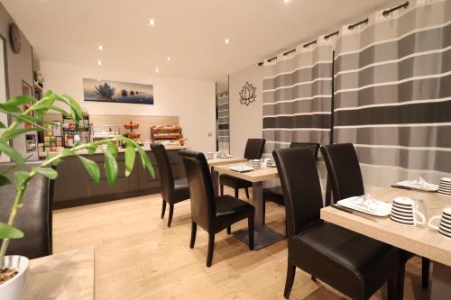 un restaurante con mesas de madera y sillas negras en Le Lotus Blanc en Albertville