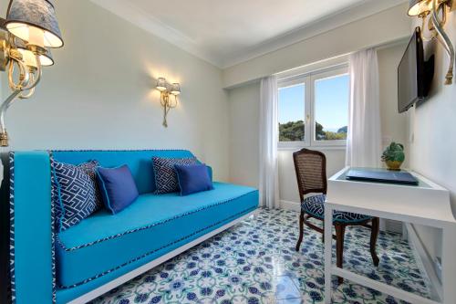 a living room with a blue couch and a desk at Grand Hotel Ambasciatori in Sorrento