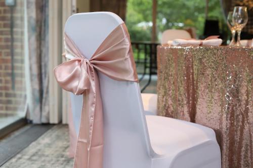 a white chair with a bow sitting next to a table at The Conningbrook Hotel in Ashford