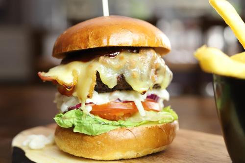 a cheeseburger with lettuce tomato and cheese next to a drink at The Conningbrook Hotel in Ashford