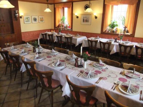 uma sala com mesas e cadeiras com toalhas de mesa brancas em Gasthof Rotes Roß em Zell im Fichtelgebirge