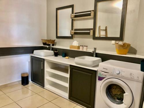 uma casa de banho com uma máquina de lavar roupa e um lavatório em COIN KREOL em Les Avirons