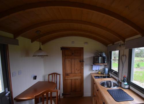 a kitchen with a sink and a wooden ceiling at Forton House Shepherd's Huts in Chard