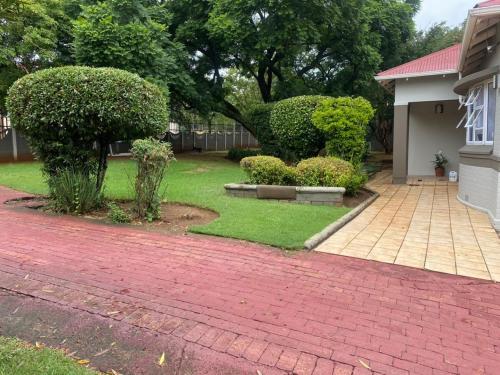 a yard with a brick driveway and a house at Paradise Guest House in Roodepoort