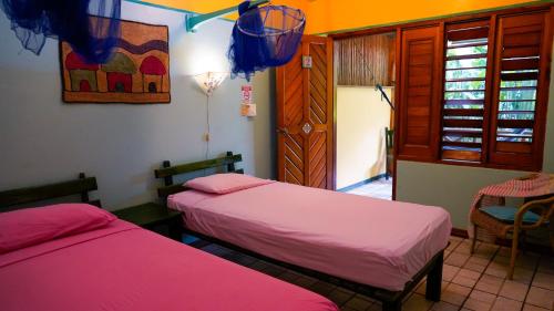 two beds in a room with pink sheets at Cabinas Guarana in Puerto Viejo