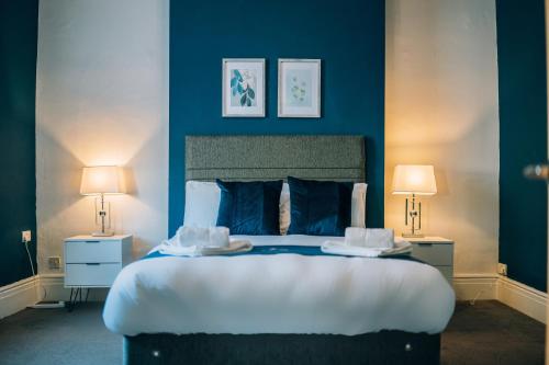 a bedroom with a large bed with blue walls at Freda House By Horizon Stays in Sunderland