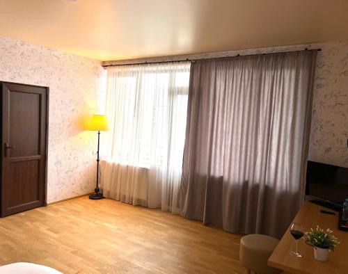 una sala de estar con una gran ventana con cortinas blancas en Green Hotel ANG, en Telavi
