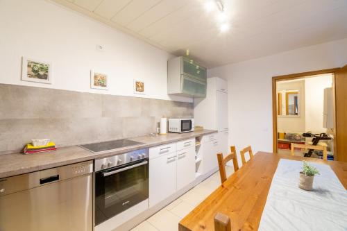 a kitchen with white cabinets and a wooden table at Ferienwohnung Alstaden in Oberhausen