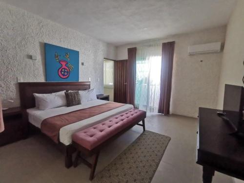 a bedroom with a large bed with a bench in it at Casa Tolok in Mérida