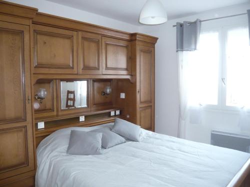 1 dormitorio con 1 cama blanca y armarios de madera en Gite de la Vallée de Mai, 