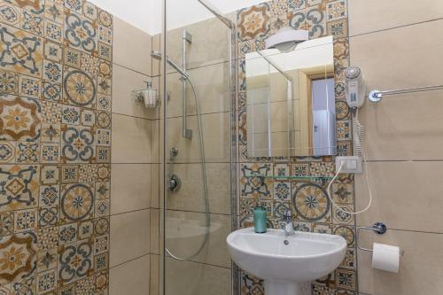 a bathroom with a sink and a shower with a mirror at B&B alla Ferrovia in Naples