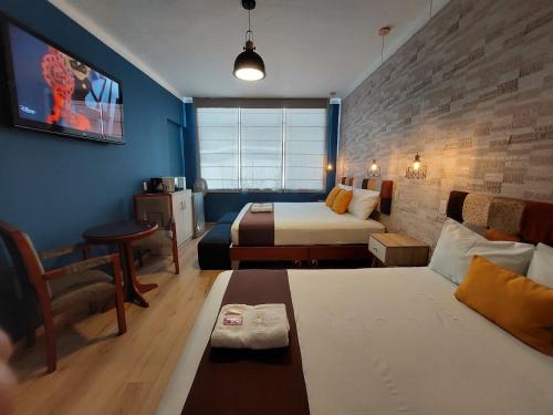 une chambre d'hôtel avec deux lits et un canapé dans l'établissement Hostal Atenea, à Ilo
