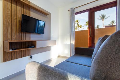 a living room with two chairs and a flat screen tv at Pousada Spa dos Amores in São Miguel do Gostoso