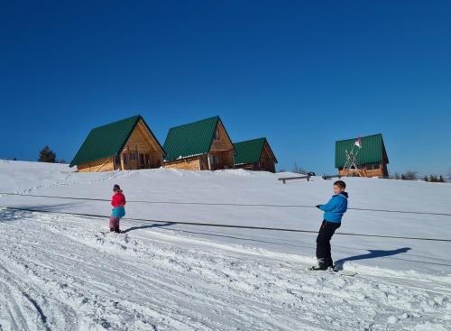 dos niños esquiando en la nieve frente a una cabaña en Markove kolibe 4, Uvac, en Sjenica