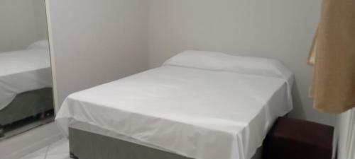 Ce lit se trouve dans un dortoir doté d'un couvre-lit blanc. dans l'établissement Pousada Ponta Negra, à Natal
