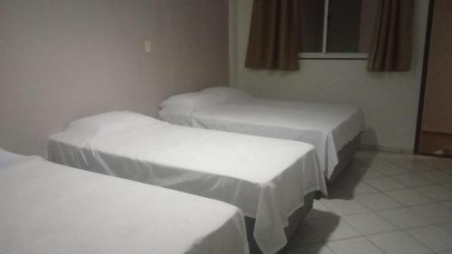 three beds in a room with white sheets at Pousada Ponta Negra in Natal