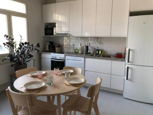 a kitchen with a table with chairs and a white refrigerator at Otavalan ullakko in Tampere