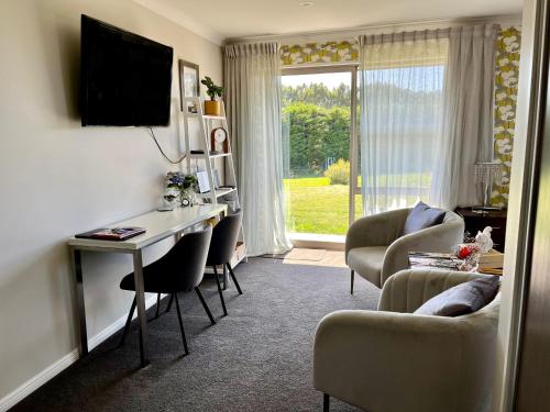 a living room with a desk and chairs and a television at Ra-ata Farm in Rangiora