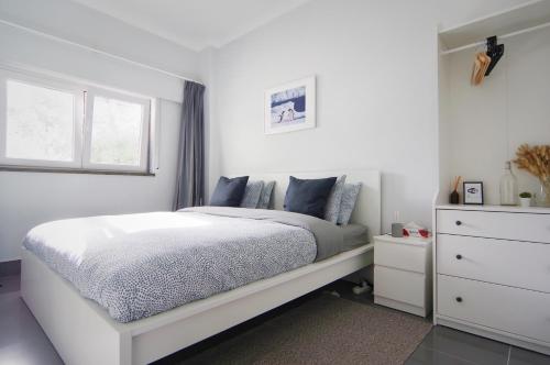 een witte slaapkamer met een bed en een raam bij Casa Emon Cascais New Mordern Apartment Two Bedrooms in Cascais