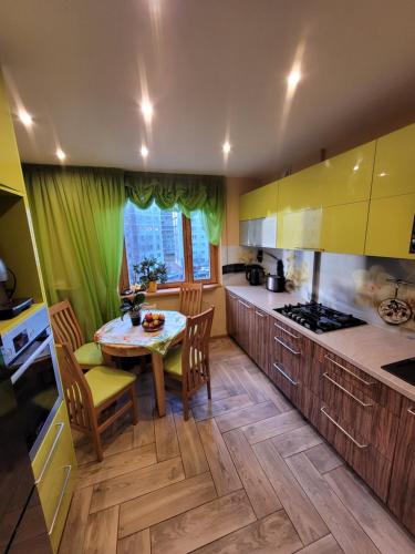 a kitchen with yellow cabinets and a table and chairs at Ulbrokas Apartment in Rīga