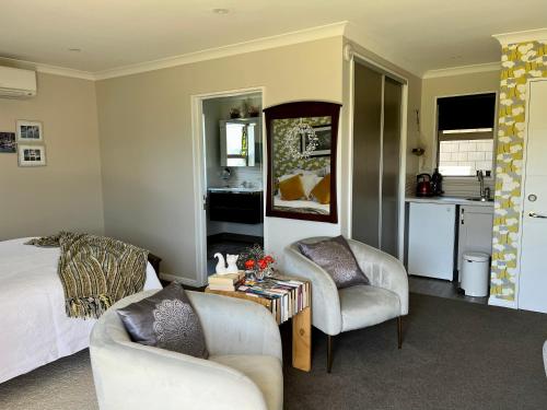 a bedroom with a bed and two chairs and a table at Ra-ata Farm in Rangiora