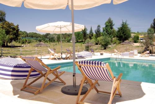 2 sillas y sombrilla junto a la piscina en Hotel Rural da Ameira, en Montemor-o-Novo