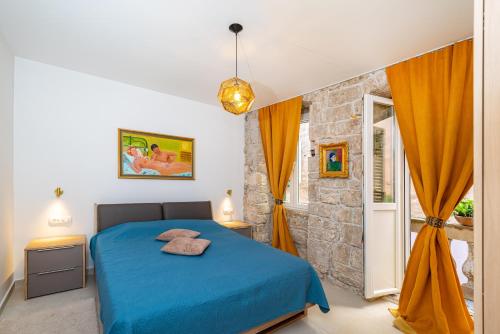 a bedroom with a blue bed and a stone wall at IDA ARTS APARTMENTS in Zadar