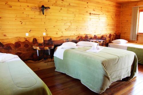 a bedroom with two beds in a log cabin at Pousada Oliveira - Cambara do Sul-RS in Cambara do Sul