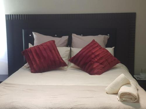 Una cama con dos almohadas rojas encima. en Fabulous guest house en Pietermaritzburg