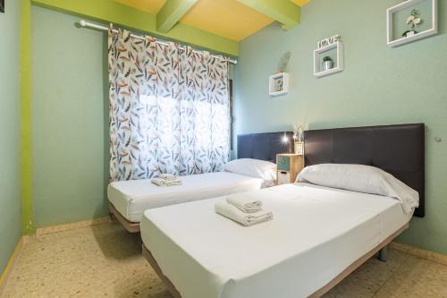 Duas camas num quarto com paredes verdes e uma janela em Lux Center 5-D em Benidorm