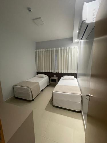 2 camas en una habitación pequeña con ventana en Lagoa EcoTowers Resort Hotel, en Caldas Novas
