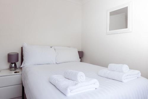 a white bed with towels on top of it at Willow Chalet near Cartmel & Lake Windermere in Flookburgh