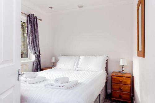 um quarto com uma cama branca com duas toalhas em Willow Chalet near Cartmel & Lake Windermere em Flookburgh