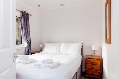 a bedroom with a white bed with two towels on it at Willow Chalet near Cartmel & Lake Windermere in Flookburgh