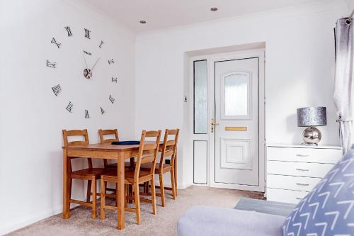 a dining room with a table and chairs and a clock at Willow Chalet near Cartmel & Lake Windermere in Flookburgh