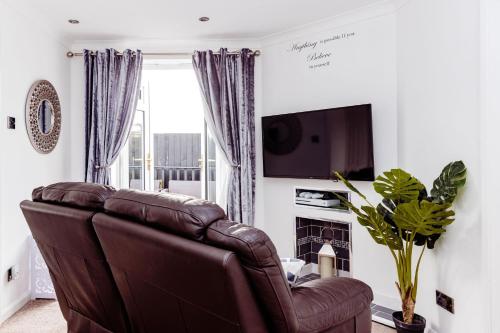 a living room with a brown leather couch and a television at Willow Chalet near Cartmel & Lake Windermere in Flookburgh