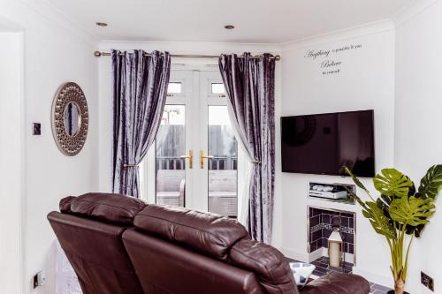 a living room with a leather couch and a television at Willow Chalet near Cartmel & Lake Windermere in Flookburgh