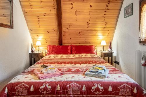 1 dormitorio con 1 cama roja y 2 toallas en CASA VACANZA "AI PIEDI DEL BOSCO", en Malborghetto Valbruna