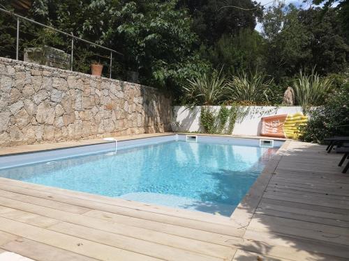 une piscine dans une arrière-cour avec un mur en pierre dans l'établissement Villa Griseor, à Porto-Vecchio