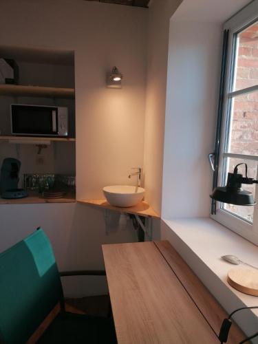 La salle de bains est pourvue d'un lavabo et d'un comptoir avec une fenêtre. dans l'établissement Mini Garni Vendémiaire, à Vesoul