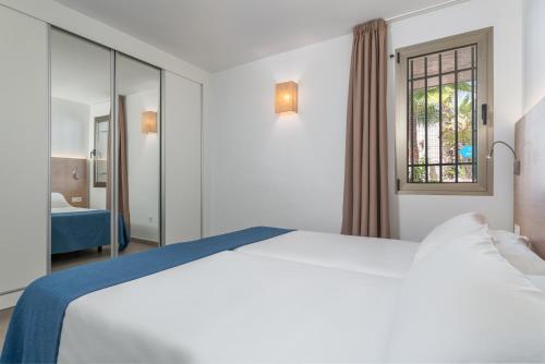 Un dormitorio con una gran cama blanca y una ventana en Apartamentos Las Buganvillas Adults Only, en Puerto Rico de Gran Canaria