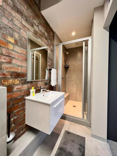 a bathroom with a white sink and a brick wall at No load-shedding Spacious Apartment in Cape Town