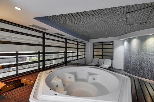 a bath tub in the middle of a room with windows at Suite at the Grand Plaza Avenida Paulista in Sao Paulo