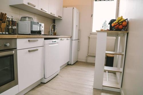 kuchnia z białymi szafkami i białą lodówką w obiekcie Le nid douillet w mieście Villemomble