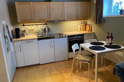 uma cozinha com armários brancos e uma mesa com cadeiras em Leilighet sentralt til Sandefjord og Torp flyplass em Sandefjord