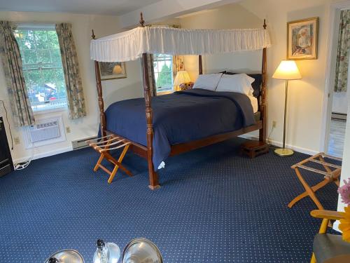 a bedroom with a canopy bed and blue carpet at Taber Inn in Mystic