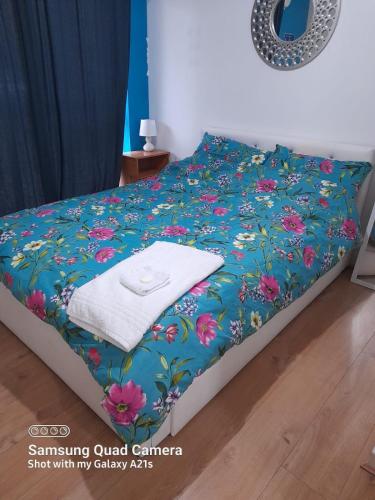 Una cama con una manta azul con flores. en Beautiful 1 bedroom Ground floor with shared bathroom, en Londres