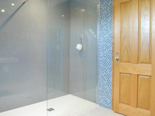 a shower with a glass door in a bathroom at Drummygar Mains in Carmyllie