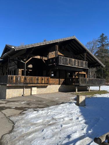 un grand bâtiment en bois avec une terrasse dans la neige dans l'établissement Les plagnettes, à Morzine