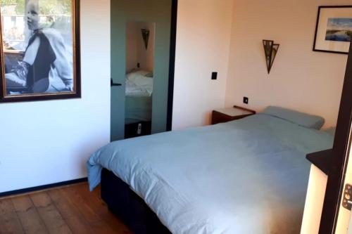 een slaapkamer met een wit bed en een spiegel bij Onthaast & Geniet in Den Helder